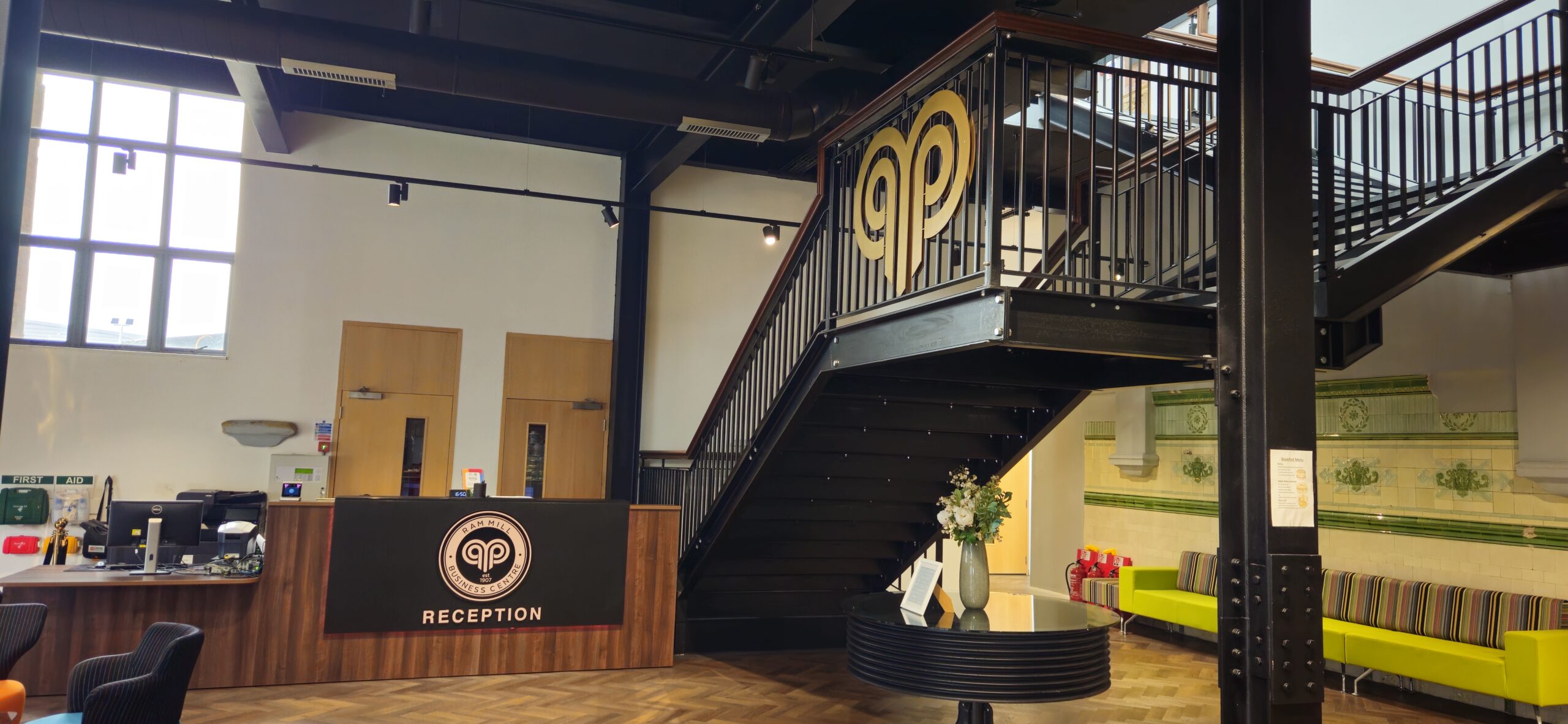 Modern reception area at Ram Mill Business Centre, Oldham, featuring industrial-style staircase and welcoming atmosphere for tenants