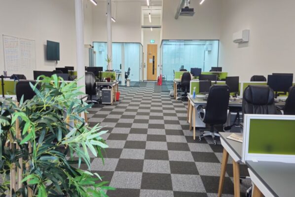 Modern open-plan office space available for rent in Oldham at Ram Mill Business Centre, featuring spacious workstations, glass meeting rooms, and vibrant greenery