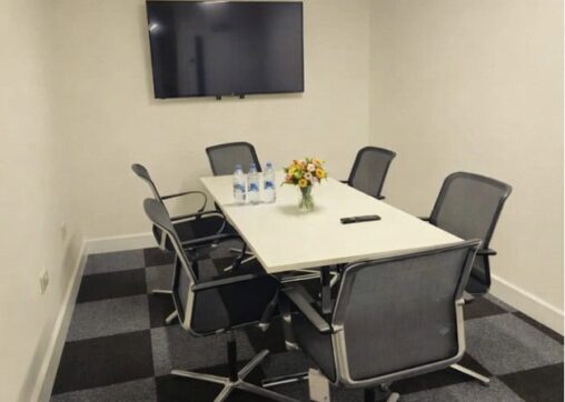 Meeting Room 4 stylish meeting room at Ram Mill Business Centre in Oldham, featuring exposed brick walls, natural light from a skylight, modern furniture, and a large screen for presentations. Perfect for business meetings, workshops, and training sessions